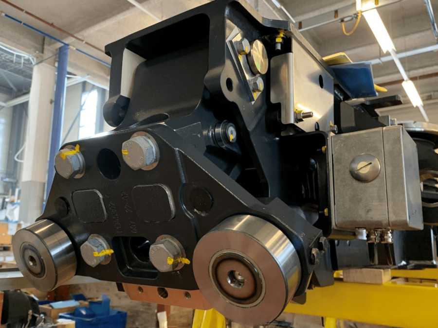 Mounted bogie swivel arm assembly with rollers and fastened components during workshop installation.